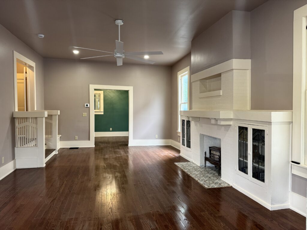 Finished living room with wood flooring, a fireplace, built-in shelves, and a green entry door after a GTex restoration project.