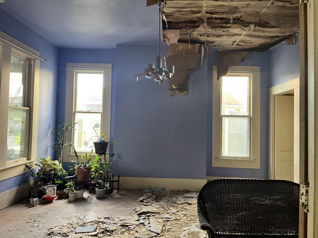 Room before restoration with ceiling damage and debris on the floor.