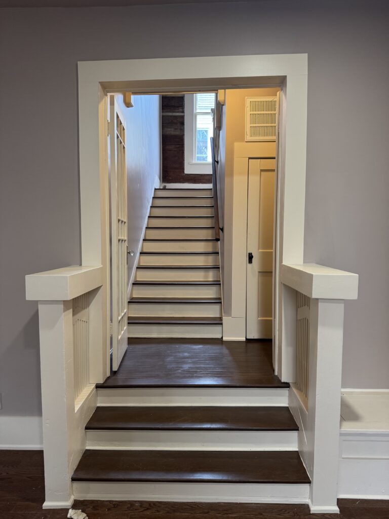 Restored stair entrance with dark wood steps and white trim.