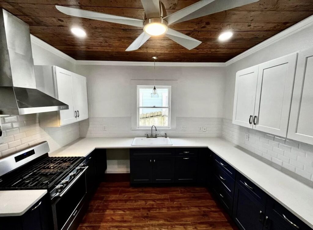 U-shaped kitchen with white upper cabinets, dark lower cabinets, light countertops and a wood ceiling.