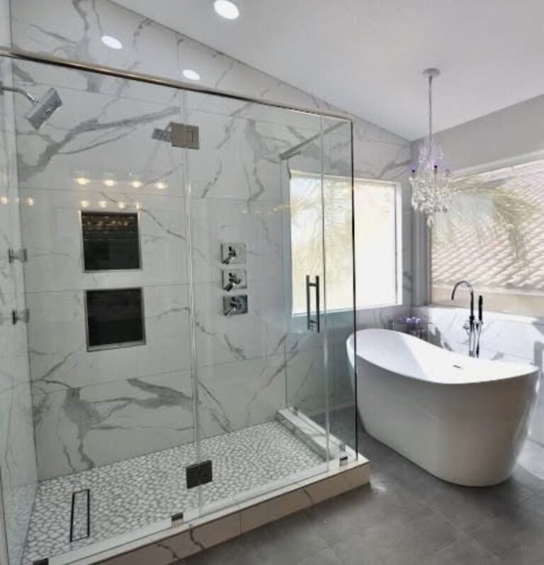 Bathroom with marble-look wall tile, a glass shower enclosure, and a freestanding white bathtub.